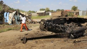 FILE - A man walks past the remains of a tank destroyed during fighting between government and rebel forces on July 10, 2016, in the Jebel area of the capital Juba, South Sudan, July 16, 2016.
