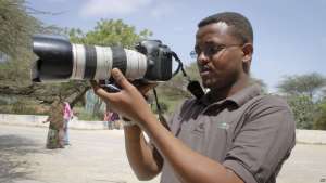 FILE - Somali journalist Mohamed Mohamud holds his camera in the Medina hospital compound in Mogadishu, Somalia, Jan. 18, 2013. Mohamud was killed on the job in 2013.