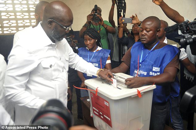 Former soccer star George Weah, Presidential candidate for the Coalition for Democratic Change, casts his vote during a Presidential runoff election in Monrovia, Liberia, Tuesday Dec. 26, 2017, Young Liberians went straight from all-night Christmas celebrations to the polls Tuesday for a runoff election between a former international soccer star and the vice president to replace Africa's first female head of state. (AP Photo/Abbas Dulleh)