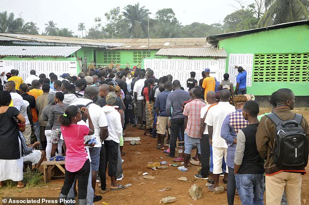 People wait to cast their votes during a Presidential runoff election in Monrovia, Liberia, Tuesday, Dec. 26, 2017. Young Liberians went straight from all-night Christmas celebrations to the polls Tuesday for a runoff election between a former international soccer star and the vice president to replace Africa's first female head of state. (AP Photo/Abbas Dulleh)