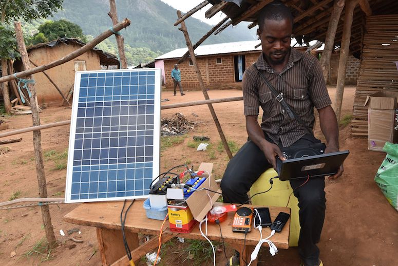 A man uses a solar energy panel to charge electric devices in Diebly, an Ivory Coast village without electricity. (Photo: Sia Kambou/AFP/Getty Images)