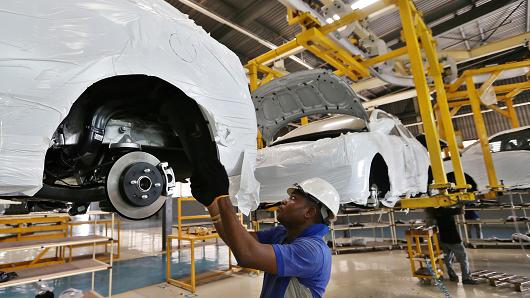 A worker fits parts to the underside of a raised Hyundai Accent car at a vehicle assembly plant in Lagos, Nigeria, on February 17, 2016.