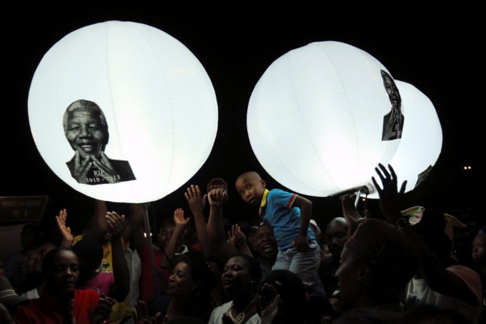 FILE PHOTO: A boy looks on in front of balloons bearing a picture of former South African President Nelson Mandela on Vilakazi Street in Soweto, South Africa, December 7, 2013. REUTERS/Siphiwe Sibeko/File FotoREUTERS